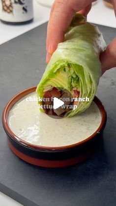 a person is dipping dressing into a lettuce wrap on top of a plate