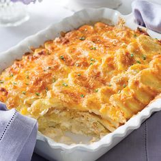 a casserole dish with cheese and potatoes in it on a purple table cloth