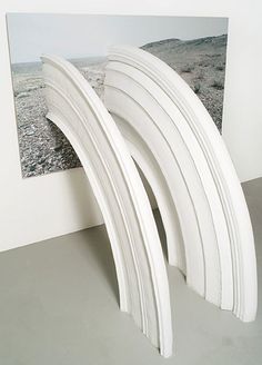 three white surfboards leaning against a wall in front of a photograph on the wall