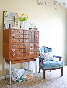 a blue chair sitting in front of a wooden filing cabinet with drawers on top of it