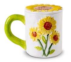 a yellow and white coffee mug with flowers painted on it's side, in front of a white background