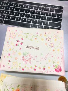 an open notebook with the word jasmine written on it next to a laptop