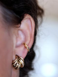 a close up of a person wearing gold earring designs on their ears and nose