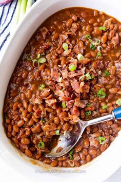 baked beans with bacon and green onions in a white casserole dish, ready to be eaten