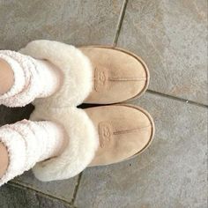 a woman's feet in slippers and socks on the ground with her legs crossed