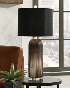 a table lamp sitting on top of a wooden table next to a brown leather chair