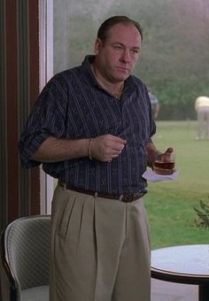 a man standing in front of a window holding a drink