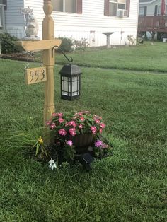 a mailbox in the grass next to a flower pot with flowers growing out of it