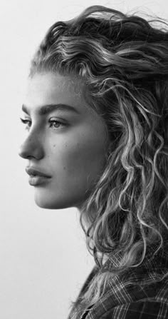 a black and white photo of a woman with curly hair looking off to the side