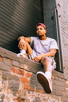 a man sitting on the ledge of a brick building with his feet propped up in front of him