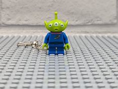 a toy alien is sitting on the floor with a keychain in front of it