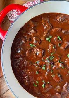 a pot filled with meat and sauce on top of a wooden table