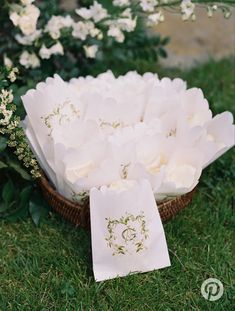 a basket filled with white flowers sitting on top of a lush green grass covered field