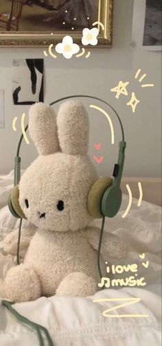 a stuffed animal with headphones on sitting on a bed in front of a painting