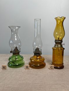 three different colored glass vases sitting next to each other on top of a table