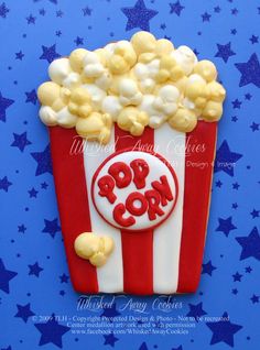 a red and white popcorn box shaped cookie on blue background with stars in the foreground