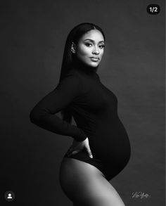 a black and white photo of a pregnant woman in tights with her hands on her hips