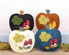 three felt pumpkins with leaves and mushrooms on them