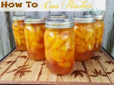 four jars filled with pickles sitting on top of a wooden table next to a cutting board