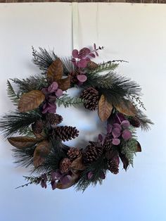 a wreath with pine cones and purple flowers