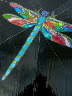 a painting of a dragonfly sitting on top of a black umbrella with multicolored wings