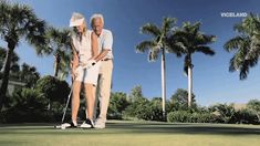 an older couple playing golf together on the green with palm trees in the back ground