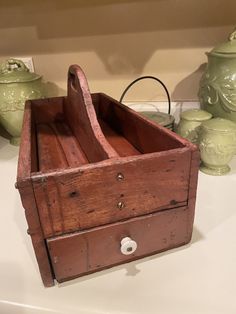 an old wooden box sitting on top of a counter next to vases and jars