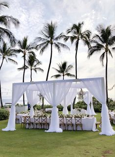 an outdoor wedding set up with white linens and draping on the grass