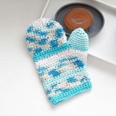 a blue and white knitted mitt sitting on top of a counter next to a plate