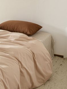 an unmade bed with two pillows on top of it and a brown comforter