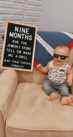 a baby sitting on a couch with a sign in front of him that says nine months