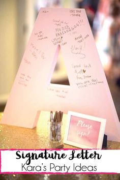 a pink letter with writing on it sitting next to a small glass jar filled with pencils