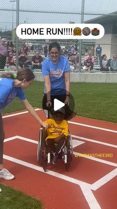 a woman pushing a boy in a wheel chair on a baseball field with people watching