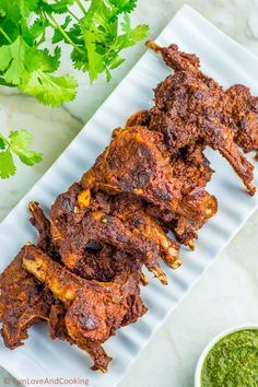 several pieces of meat on a white plate with cilantro