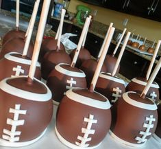 chocolate covered football candies with wooden sticks sticking out of them on a table in a kitchen