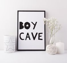 a black and white poster with the word boy cave next to it, on a shelf