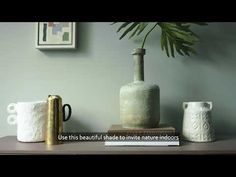 two vases sitting on top of a table next to books and a potted plant