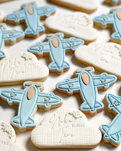 cookies decorated with blue and white icing are arranged in rows on a table top