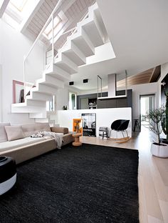 a living room filled with lots of furniture and a staircase leading up to the top floor