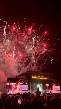 fireworks are lit up in the night sky above a stage with people on it and lights