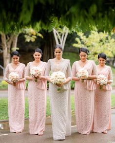 a group of women standing next to each other holding bouquets in their hands and wearing pink dresses