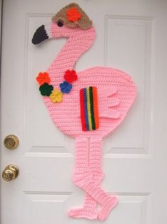 a crocheted pink flamingo is hanging on the front door with pom poms