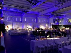 an indoor event venue with white tables and purple lighting