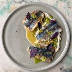 a plate with some fish on it and sauce in the middle, sitting on a table