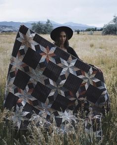 a woman holding up a quilt in a field