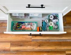 an organized drawer in a white cabinet with lots of crafting supplies on the bottom shelf