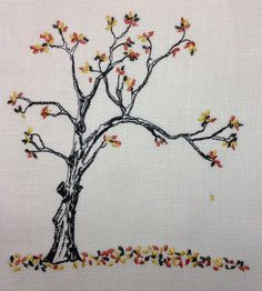 a cross stitch picture of a tree with yellow and red leaves on it's branches