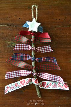 a christmas tree made out of ribbon on top of a wooden table with an ornament hanging from it