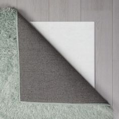 an area rug on the floor with a white and gray carpet next to it in front of a wooden wall