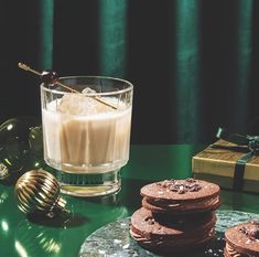 some cookies are sitting on a table next to a glass of milk and christmas decorations